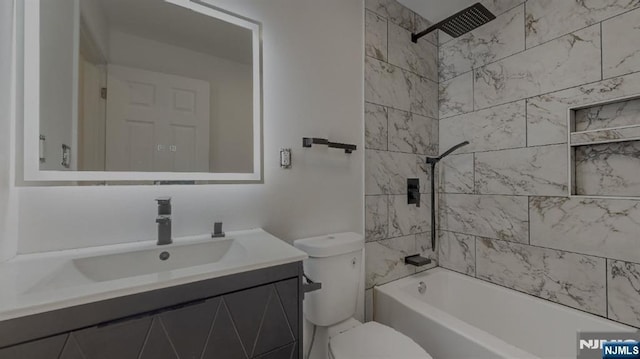 full bathroom featuring tiled shower / bath, vanity, and toilet