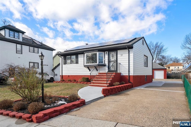 view of front facade with a garage, an outdoor structure, a front yard, and solar panels