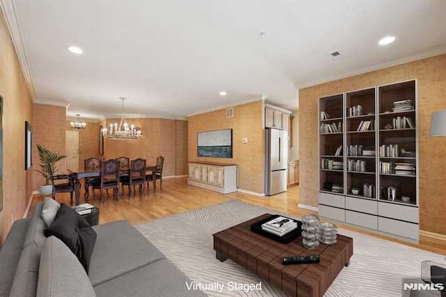 living room with a notable chandelier, hardwood / wood-style flooring, and ornamental molding