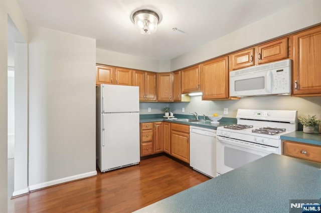 kitchen featuring dark countertops, white appliances, a sink, and dark wood-style flooring