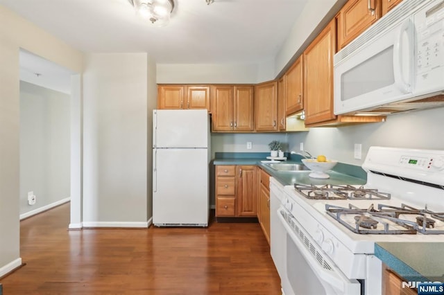 kitchen with white appliances, a sink, baseboards, dark wood-style floors, and brown cabinetry