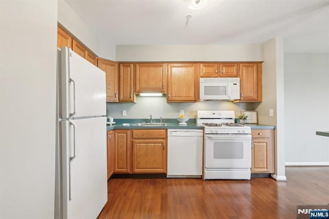 kitchen with brown cabinetry, dark wood finished floors, white appliances, and a sink