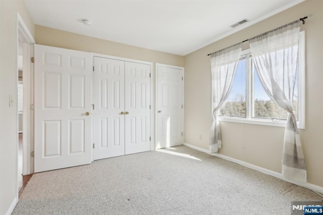 unfurnished bedroom featuring light carpet, visible vents, and baseboards