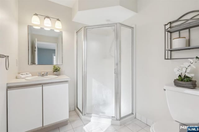 full bathroom featuring toilet, vanity, baseboards, tile patterned floors, and a stall shower