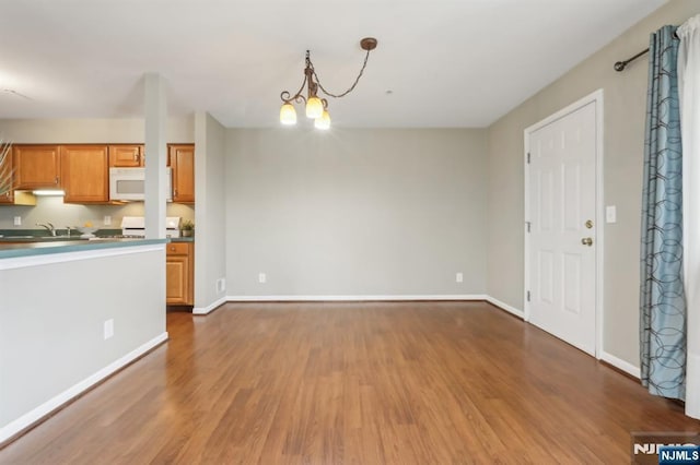 kitchen featuring white microwave, dark wood-style floors, a sink, and stove