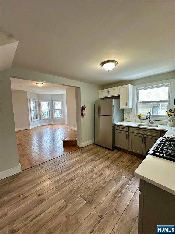 kitchen featuring sink, a wealth of natural light, stainless steel refrigerator, and light hardwood / wood-style flooring