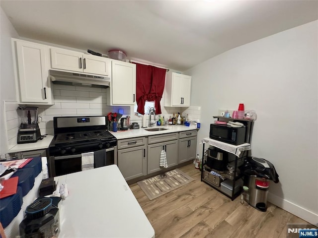 kitchen featuring gray cabinets, sink, decorative backsplash, light hardwood / wood-style floors, and gas range