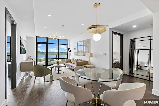 dining area with an inviting chandelier, a wall of windows, dark hardwood / wood-style floors, and a water view