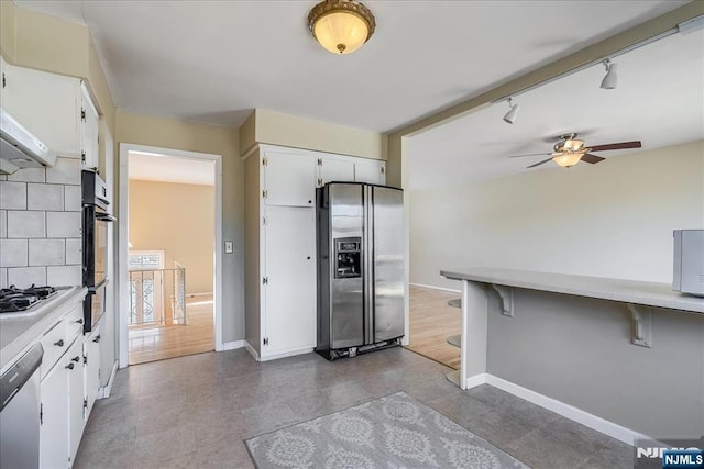 kitchen with rail lighting, ceiling fan, white cabinetry, stainless steel appliances, and decorative backsplash