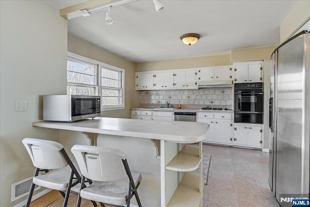 kitchen with appliances with stainless steel finishes, sink, white cabinets, and backsplash