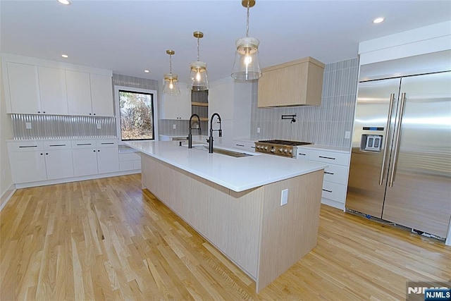 kitchen with light wood-type flooring, stainless steel built in fridge, a sink, and modern cabinets