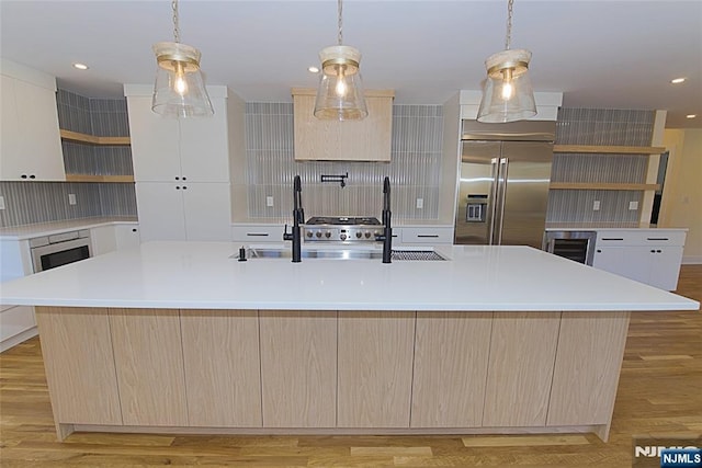 kitchen with light wood finished floors, decorative backsplash, stainless steel built in refrigerator, light countertops, and open shelves