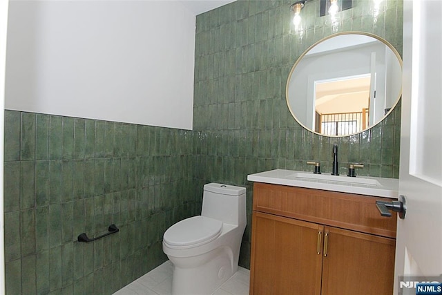 bathroom featuring toilet, vanity, and tile walls