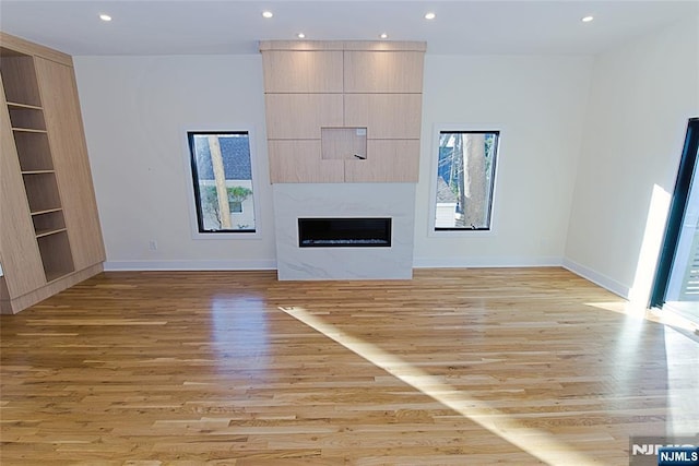 unfurnished living room with light wood-style floors, recessed lighting, and a large fireplace