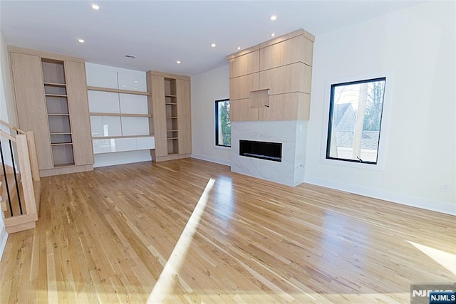 unfurnished living room with recessed lighting, a fireplace, light wood-style flooring, and baseboards