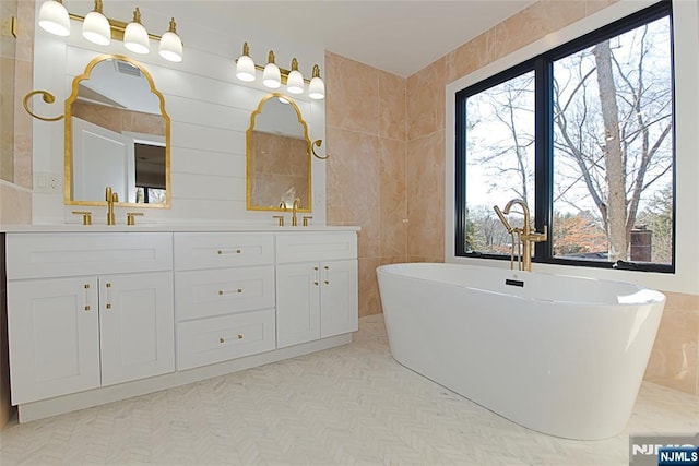 bathroom with double vanity, a soaking tub, and a sink