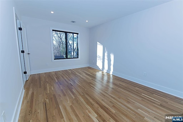 spare room featuring light wood finished floors, recessed lighting, visible vents, and baseboards