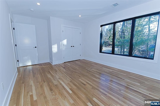 spare room featuring light wood-type flooring, baseboards, visible vents, and recessed lighting