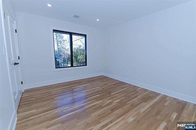 spare room featuring recessed lighting, wood finished floors, visible vents, and baseboards