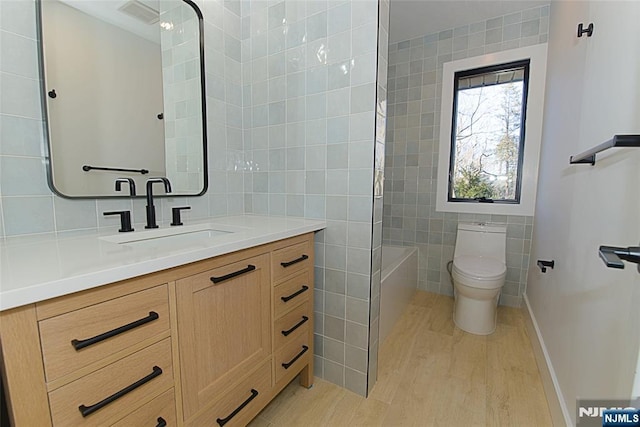 bathroom featuring wood finished floors, tile walls, toilet, and vanity