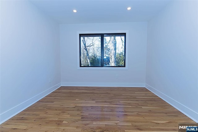 spare room featuring baseboards, wood finished floors, and recessed lighting