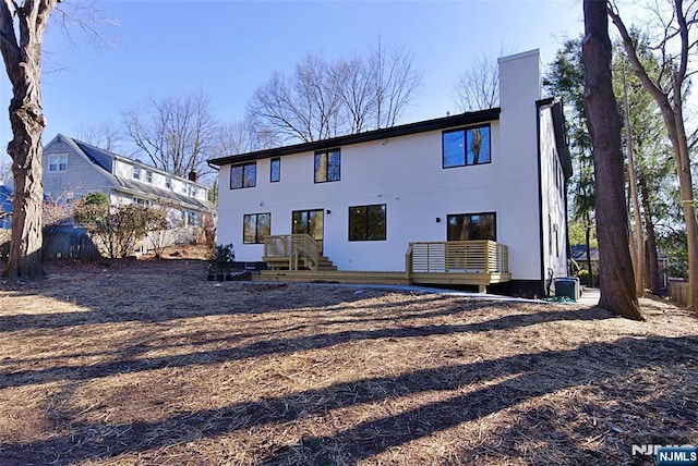 rear view of property with a chimney and stucco siding