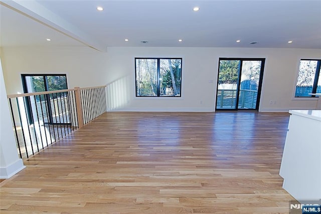 spare room with recessed lighting, visible vents, light wood-style flooring, beamed ceiling, and baseboards