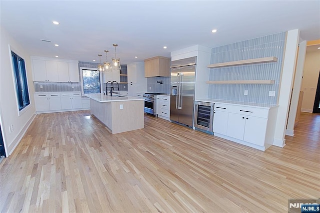 kitchen with premium appliances, wine cooler, light wood-type flooring, and a sink