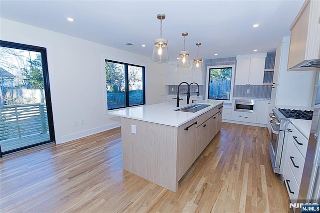 kitchen featuring stainless steel appliances, a sink, light countertops, a wealth of natural light, and modern cabinets