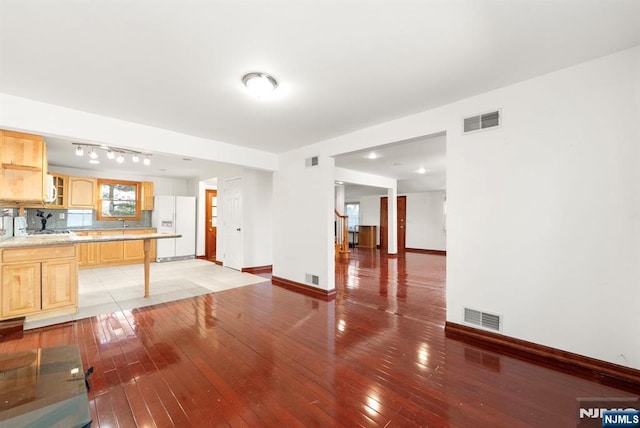 kitchen with light brown cabinetry, backsplash, white refrigerator with ice dispenser, and light hardwood / wood-style floors