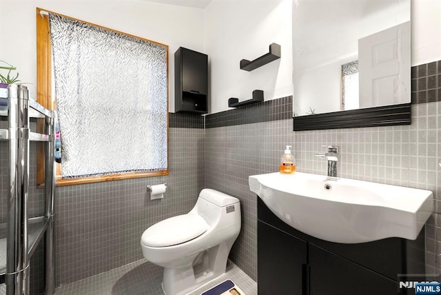 bathroom with vanity, a healthy amount of sunlight, tile walls, and toilet