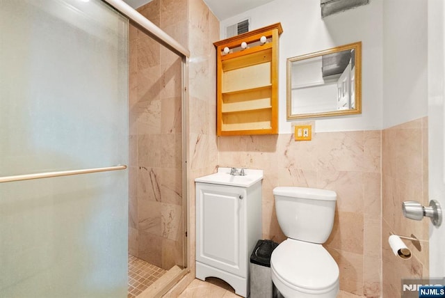 bathroom with a shower with door, vanity, tile walls, and toilet