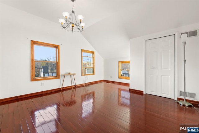 additional living space with an inviting chandelier, lofted ceiling, and dark hardwood / wood-style flooring