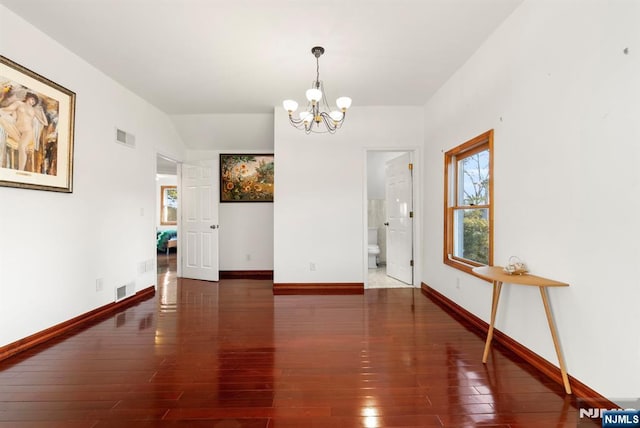 unfurnished dining area with lofted ceiling, dark hardwood / wood-style floors, and a chandelier