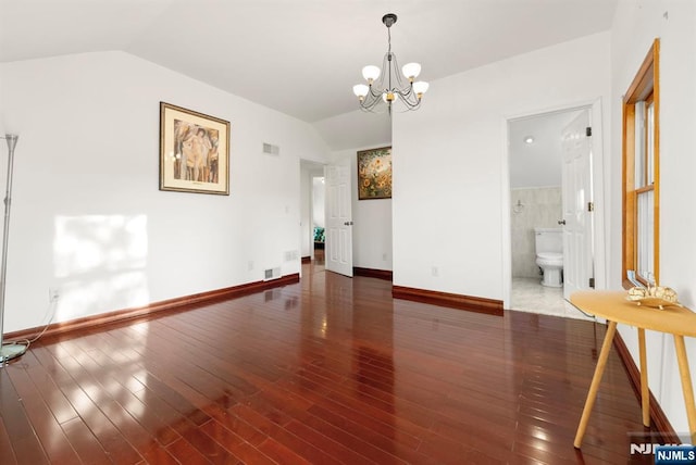 unfurnished room featuring vaulted ceiling, dark hardwood / wood-style floors, and an inviting chandelier