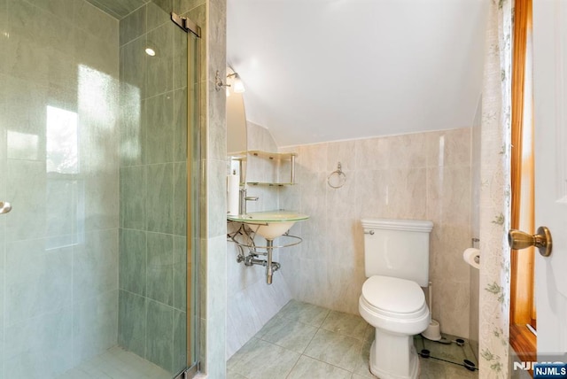 bathroom with lofted ceiling, tile patterned flooring, tile walls, and toilet