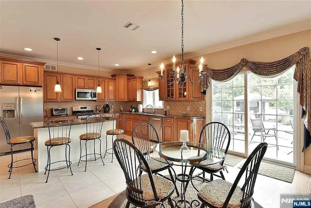 dining space featuring a notable chandelier, a toaster, visible vents, and crown molding