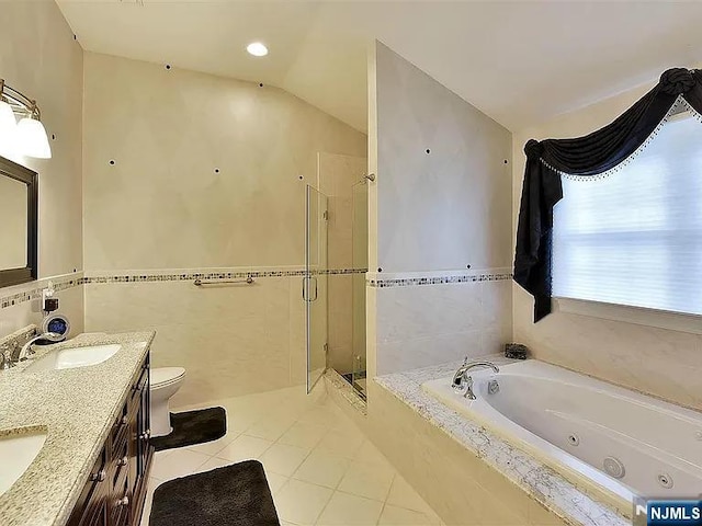 bathroom featuring a stall shower, toilet, a sink, tile patterned flooring, and tile walls