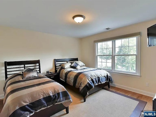 bedroom featuring wood finished floors, visible vents, and baseboards