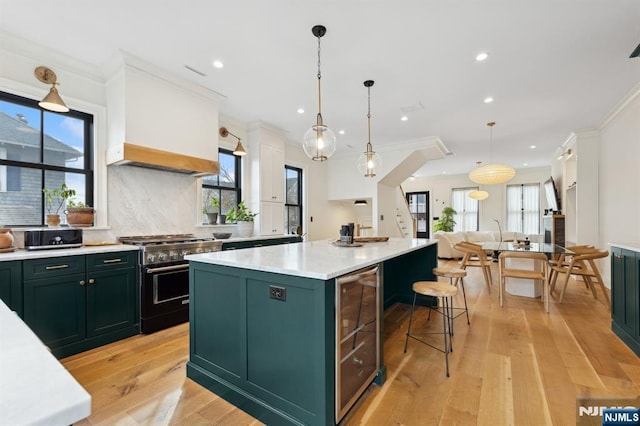 kitchen with a center island, light wood-type flooring, stainless steel range, ornamental molding, and pendant lighting