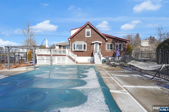 view of front of property featuring a pergola, a patio, and a covered pool