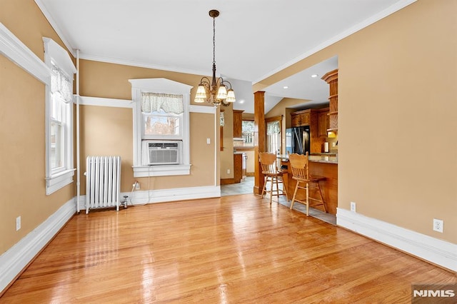 interior space with ornate columns, radiator, light wood-type flooring, cooling unit, and an inviting chandelier