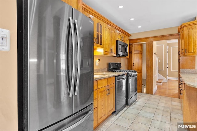 kitchen with light stone counters, appliances with stainless steel finishes, and light tile patterned floors