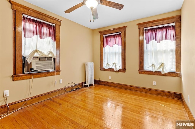 unfurnished room featuring ceiling fan, radiator, cooling unit, and light hardwood / wood-style floors