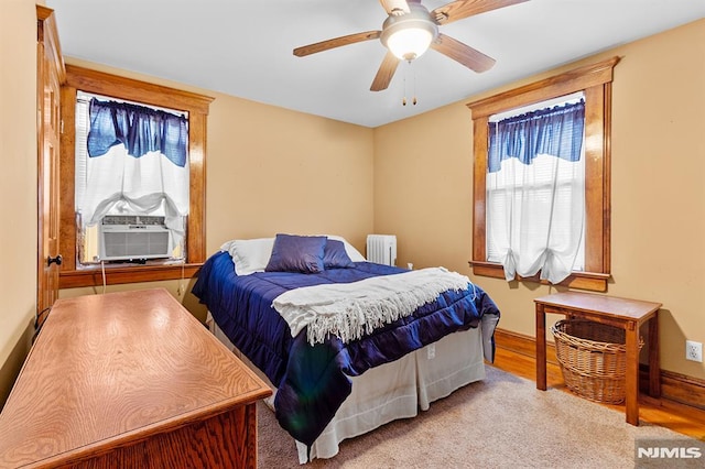 bedroom with cooling unit, radiator heating unit, and ceiling fan