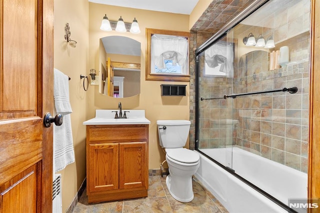 full bathroom featuring toilet, vanity, and bath / shower combo with glass door