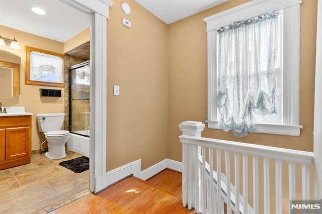 full bathroom featuring plenty of natural light, toilet, and combined bath / shower with glass door