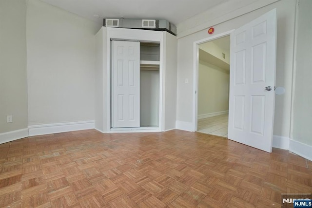 unfurnished bedroom featuring a closet and light parquet floors