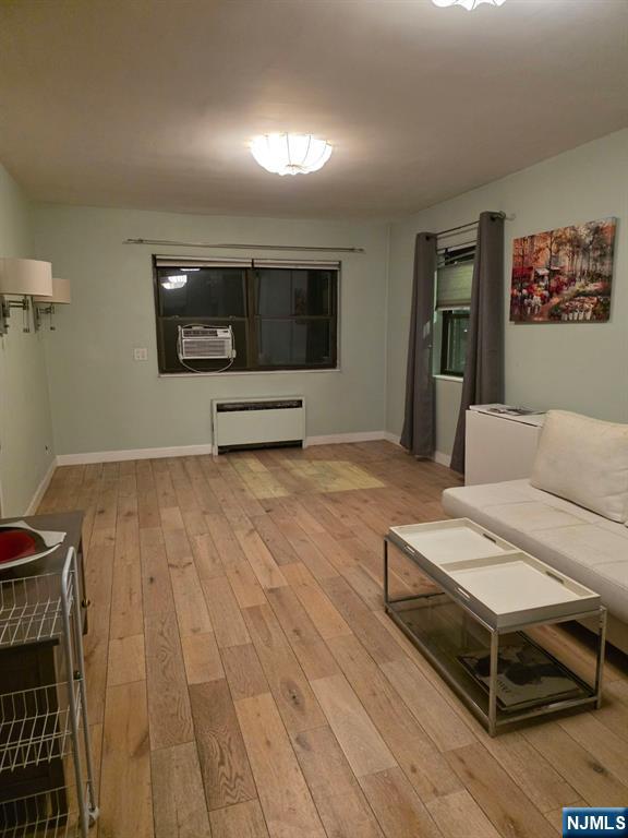 living room featuring cooling unit, radiator heating unit, and light hardwood / wood-style floors