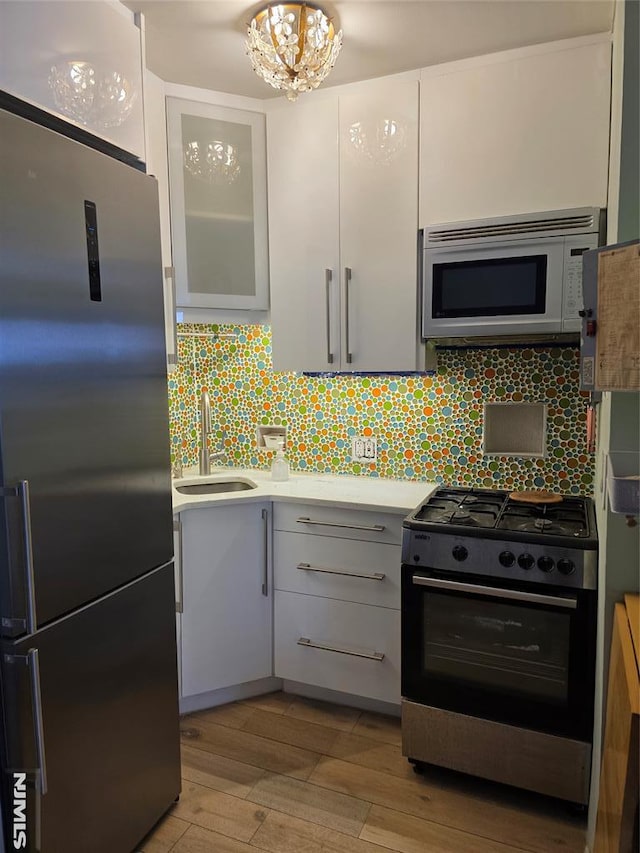 kitchen featuring sink, gas stove, white cabinets, decorative backsplash, and high end refrigerator